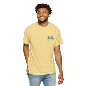 A man wearing the BODE Summer Camp T-Shirt 2026 "Life's Better Together" by Printify stands against a plain background, smiling. The light yellow heavyweight cotton tee features a small colorful graphic and text on the left chest.