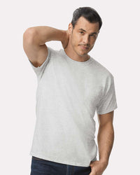 A man wears a light gray Gildan 2300 Unisex Ultra Cotton® Pocket T-Shirt with a custom screen printed logo and dark jeans, standing against a plain white background.