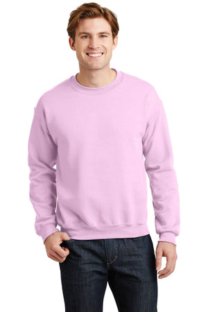 A person wearing a Gildan Heavy Blend Crewneck Sweatshirt 18000 in light pink and jeans stands against a plain white background.