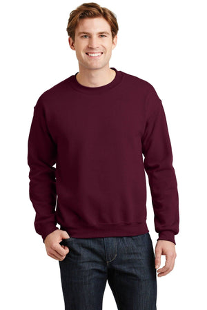 A person wearing a Gildan Heavy Blend Crewneck Sweatshirt 18000 in maroon and dark jeans stands smiling against a plain white background.