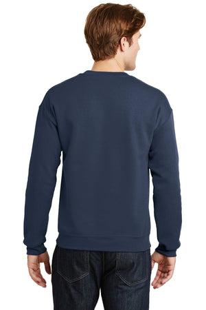 A person wearing a Gildan Heavy Blend Crewneck Sweatshirt 18000 in navy blue and dark jeans stands facing away from the camera.