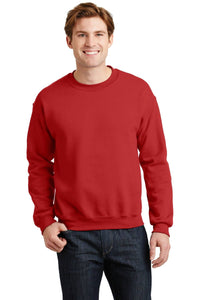 A person wearing a red Gildan Heavy Blend Crewneck Sweatshirt 18000 and jeans stands and smiles.