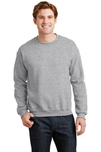 A person wearing a Gildan Heavy Blend Crewneck Sweatshirt 18000 in gray and dark jeans smiles at the camera.