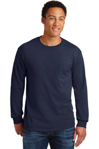 A person wearing blue jeans and a navy Gildan Ultra Cotton 100% Cotton Long Sleeve T-Shirt with Pocket (Pack of 36, style 2410, custom screen printed logo included) stands against a plain white background.