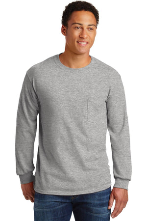 Man in a light gray Gildan Ultra Cotton Long Sleeve T-Shirt with Pocket (Pack of 36), standing and smiling. Ideal for anyone seeking comfortable, custom screen printed logo tees for everyday wear.