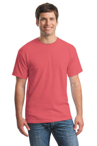 A man, smiling and facing forward, wears a Gildan Heavy 100% Cotton Custom T-Shirt (Gildan 5000) in coral pink with blue jeans against a white background.