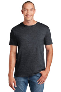 A smiling person stands with one hand in their pocket, wearing a dark gray Gildan Softstyle T-Shirt 64000, made from ring spun cotton, and blue jeans, showcasing a modern classic fit.