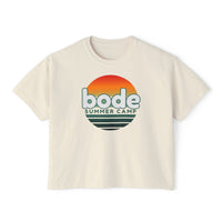 The 2026 Bode Summer Bootcamp - Cali Sunset Logo Crop T-Shirt by Printify features a boxy, cropped fit and soft ring-spun cotton, with "bode SUMMER CAMP" text and a sunset graphic in orange, yellow, and green.