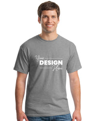 A man wears a Gildan 5000 Heavy 100% Cotton Custom T-Shirt (Pack of 36) with "Your Design Here" in white, ideal for adding your custom logo, against a white background. Custom screen printed logo included.