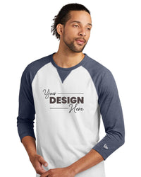 A man in a white and blue New Era Cotton Blend 3/4-Sleeve Baseball Raglan T-Shirt (NEA121) with "Your Design Here" stands against a plain white background, highlighting the ideal canvas for your custom New Era style.