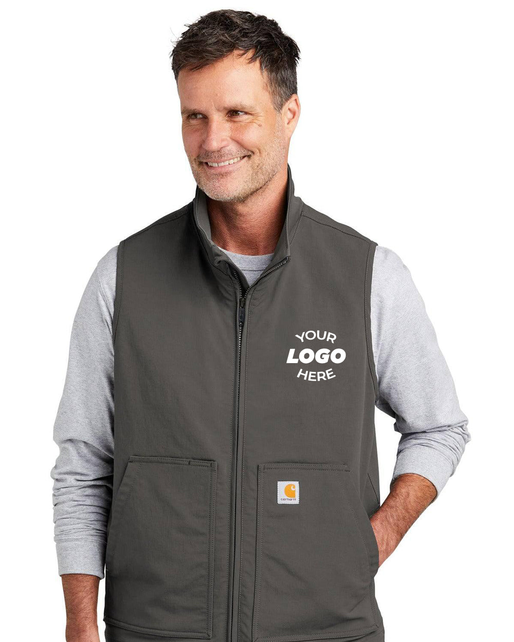 A man models the Carhartt Super Dux Soft Shell Vest CT105535 over a light gray shirt, with “Your Logo Here” on the left chest and a Carhartt label near the pocket, highlighting Carhartt's renowned durability.