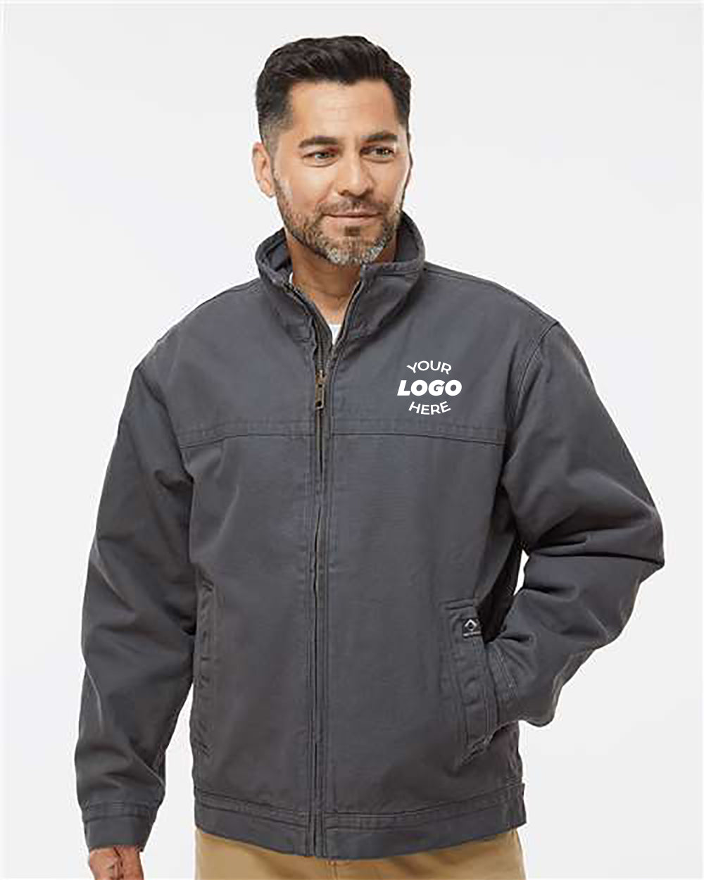 A man with black hair and a beard wears a dark gray Dri Duck Maverick Boulder Cloth Jacket with Blanket Lining from DRI DUCK, featuring "Your Logo Here" printed on the left chest area. Made from durable Boulder Cloth™ canvas, this jacket is perfect for any job. He is posing against a plain white background.