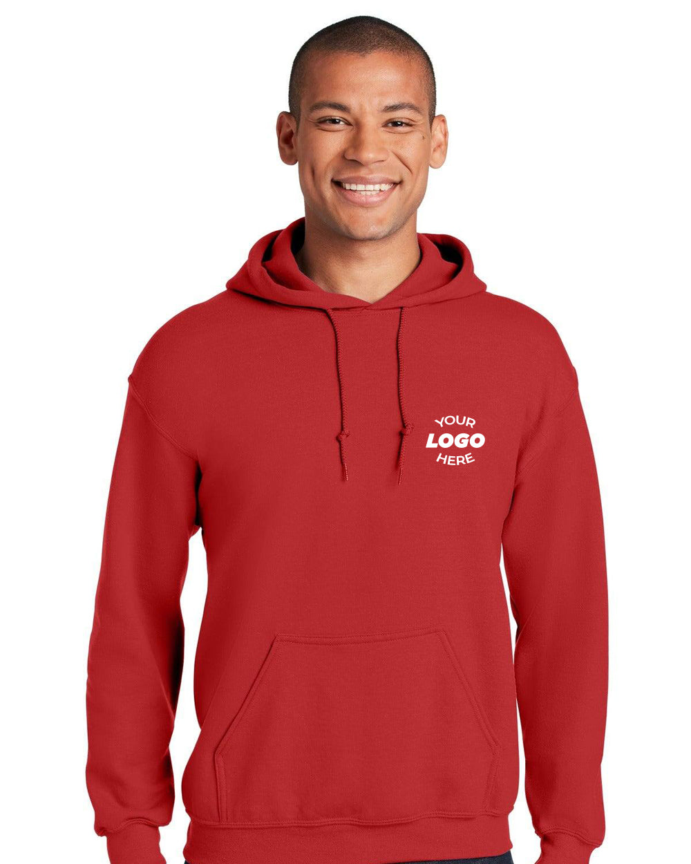 A person stands smiling in a vibrant red Gildan - Heavy Blend Hoodie Sweatshirt 18500 with "Your Logo Here" on the front, blending durable cotton/poly comfort with unique style.
