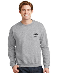 A person is wearing a gray Gildan Heavy Blend Crewneck Sweatshirt 18000 with "Your Logo Here" emblazoned on the chest, standing against a plain white background.