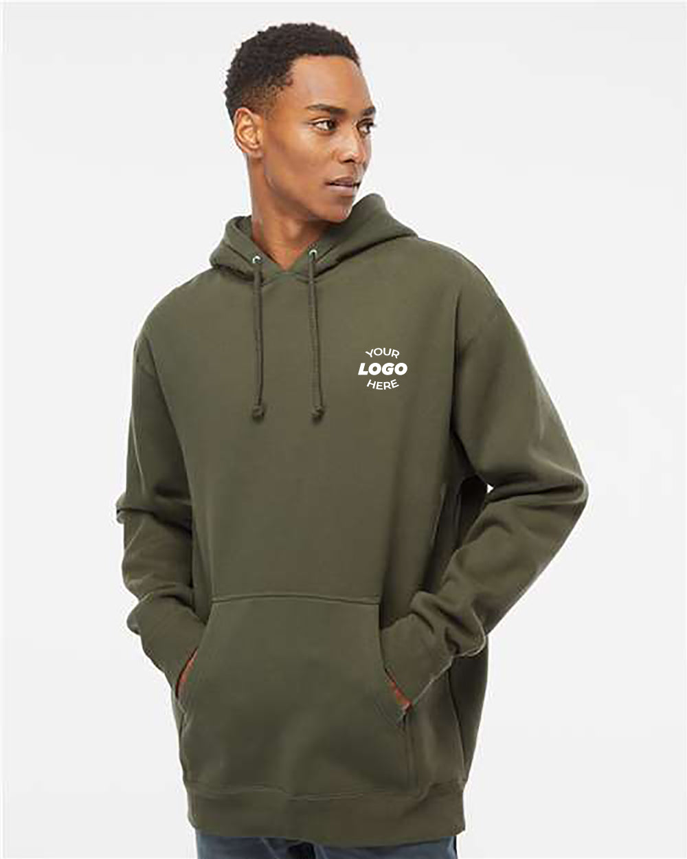 A person wearing an olive-green Independent Trading Co. Heavyweight Hoodie Sweatshirt with fleece lining and the "Your Logo Here" text printed on the left chest, standing against a plain background.