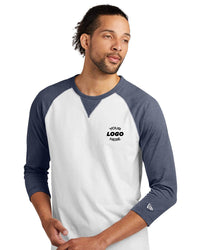 Person wearing a New Era Cotton Blend 3/4-Sleeve Baseball Raglan T-Shirt (NEA121) in white and blue with "Your Logo Here" text on the chest, crafted from a sueded cotton blend.