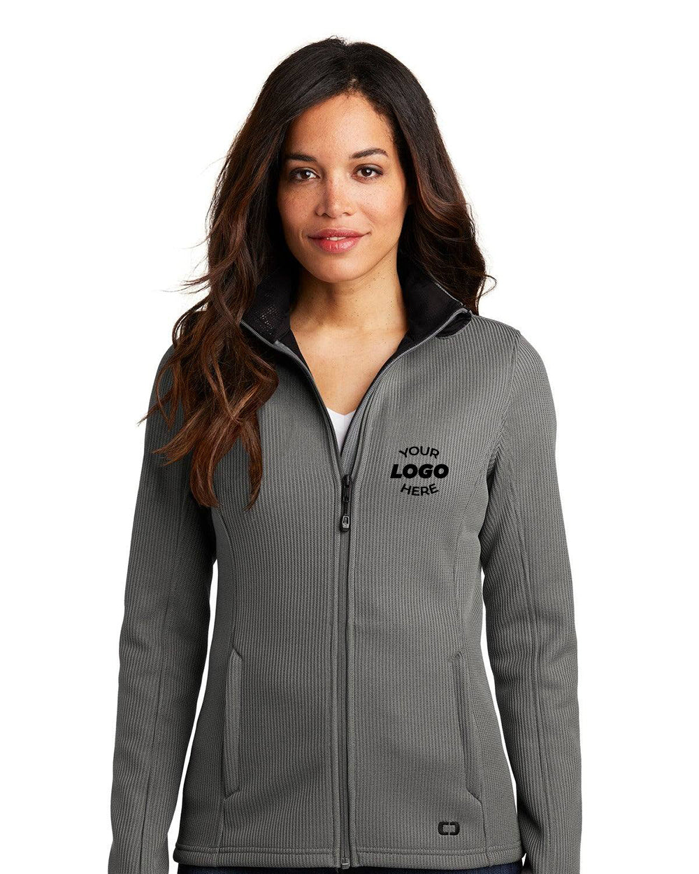 A woman models the OGIO Ladies Grit Fleece Jacket LOG727, a gray poly knit zip-up with a cadet collar and "YOUR LOGO HERE" on the left chest, against a plain white background.