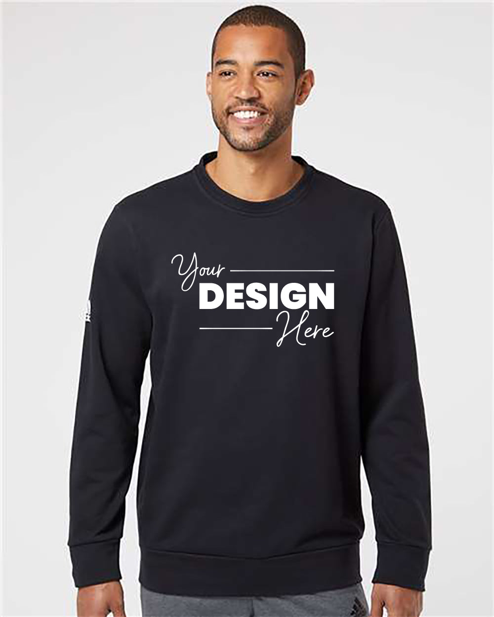 A man wearing an Adidas Fleece Crewneck Sweatshirt made from recycled polyester with the text "Your Design Here" printed on the front.