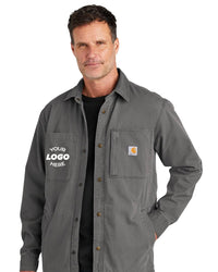 A man wearing the Carhartt Rugged Flex Fleece-Lined Shirt Jacket CT105532, featuring a logo space and small chest label. The gray button-up design provides a fleece-lined interior for outdoor activities and incorporates Rugged Flex technology for added durability and comfort.