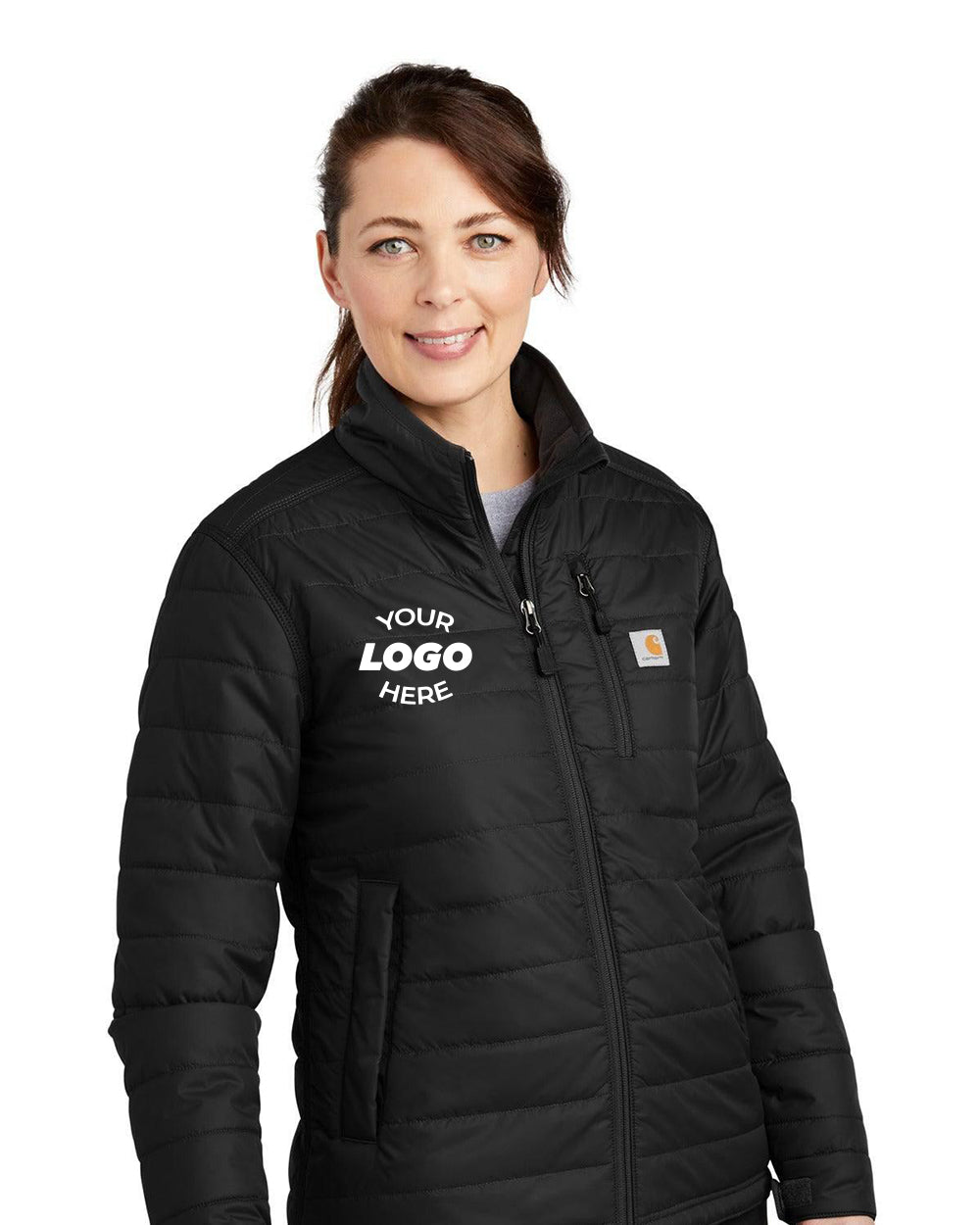 A woman wears the Carhartt Women's Gilliam Jacket CT104314, a black quilted jacket featuring Wind Fighter technology, a customizable "Your Logo Here" area, and a small Carhartt logo on the chest.
