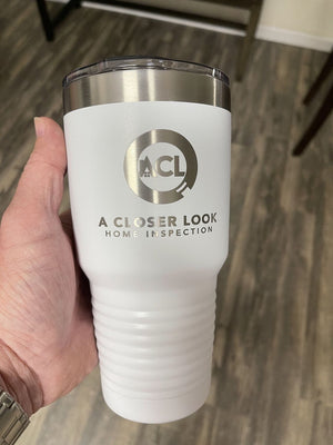 A hand holds a Kodiak Coolers Custom Tumbler 20 oz with your Logo or Design Engraved - Special Bulk Wholesale Pricing - Pack of 24 Pieces - 1 Color - $14.85 Each, with the text "A CLOSER LOOK HOME INSPECTION" printed on it. The custom tumbler features a silver lid, a ribbed lower section, and is laser engraved for a sleek finish.