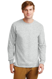 A man faces forward in a Gildan 100% US Cotton Long Sleeve T-Shirt 2400 (Pack of 36, custom screen printed logo included) and tan pants, standing against a plain white background.