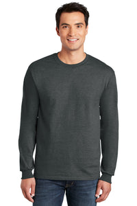 A man smiles facing forward, wearing blue jeans and a charcoal gray Gildan 2400 long-sleeve crew neck—made from 100% US cotton, with a custom screen printed logo included (Pack of 36).