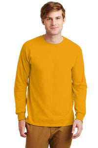 A man wears a mustard yellow Gildan 100% US Cotton Long Sleeve T-Shirt 2400 (pack of 36, custom screen printed logo included) and brown pants, standing facing forward against a white background.