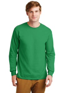 A man wearing a Gildan 2400 long sleeve T-shirt in green, made from 100% US cotton with a custom screen-printed logo, and brown pants stands facing forward against a white background.