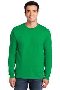 A man wearing a plain green Gildan 100% US Cotton Long Sleeve T-Shirt 2400 (pack of 36, custom screen printed logo included) and jeans stands facing forward, smiling at the camera.