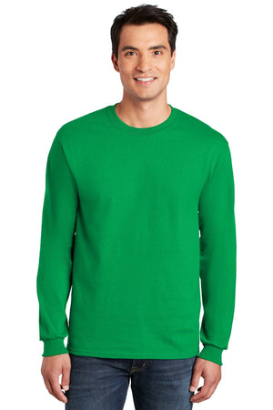 A man wearing a plain green Gildan 100% US Cotton Long Sleeve T-Shirt 2400 (pack of 36, custom screen printed logo included) and jeans stands facing forward, smiling at the camera.