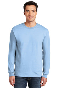 A man in jeans smiles at the camera, wearing a light blue Gildan 100% US Cotton Long Sleeve T-Shirt (Pack of 36, Style 2400) with custom screen printed logo, against a plain white background.