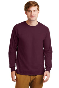 A man faces forward in a plain setting, wearing tan pants and a maroon Gildan 2400 long-sleeve crewneck shirt made from 100% US cotton, featuring a custom screen-printed logo.