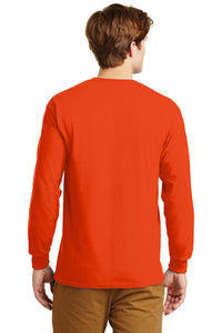 A man stands facing away, wearing a Gildan 100% US cotton long sleeve orange T-shirt (Pack of 36, style 2400) with custom screen printed logo, and tan pants.