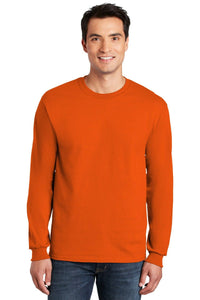 A man is wearing a Gildan 100% US Cotton Long Sleeve T-Shirt 2400 with a custom screen printed logo and blue jeans, standing against a white background.