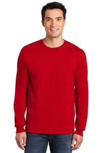 A man in jeans and a plain red long-sleeve shirt smiles, modeling the Gildan (Pack of 36) 100% US Cotton Long Sleeve T-Shirt 2400, which includes custom screen printed logos.
