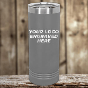 A grey insulated tumbler with "Custom Logo 22 oz Skinny Tumbler - Front side Logo Included" displayed on it, resting on a wooden surface against a blurred wooden background, perfect as a promotional gift by Kodiak Coolers.
