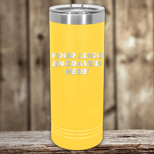 Yellow insulated Custom Logo 22 oz Skinny Tumbler with "your custom logo engraved here" text on a wooden surface, against a blurred background by Kodiak Coolers.