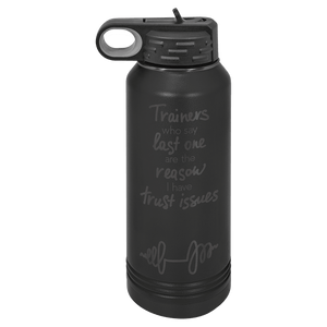 The NEW ION Plated Tumblers by Kodiak Coolers, custom engraved drinkware with the special engraving color "Ghost Black & Rose Gold," features a black water bottle with a handle on the lid and the humorous text: "Trainers who say last one are the reason I have trust issues." This stylish accessory is perfect as a logo promotional gift for fitness enthusiasts or those looking to add a touch of humor to their daily routine.
