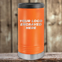 An orange insulated stainless steel can holder by Kodiak Coolers, featuring your engraved logo on the front, a black lid, and silver base. 4th of July SALE – Custom Logo Drinkware, $200 minimum order. Placed on a wooden surface with blurred wood background.
