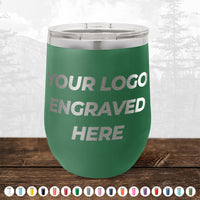 Kodiak Coolers' 12 oz stemless wine cup is shown in green with "YOUR LOGO ENGRAVED HERE" on the front, displayed on wood. Multiple colors available—ideal for custom engraved mugs for your brand. No minimum order, sample volume pricing offered.