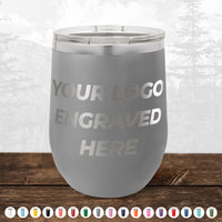 A gray Kodiak Coolers 12 oz stemless wine cup with your logo engraved sits on a wooden surface, color options below—ideal for custom branding with no minimum order.