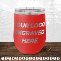 A red, stainless steel tumbler with "Your Logo Engraved Here" text, set on a wooden surface with a monochrome mountain background and color options displayed at the bottom. Ideal for promotional gifts or custom logo mugs enthusiasts. Introducing the 4th of July SALE - Engraved Custom Logo Drinkware - Front Engraved Logo Included - $250 Minimal Order by Kodiak Coolers.
