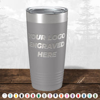 Explore our gray insulated Kodiak Coolers tumbler with a laser-etched "Your Logo" design, ideal for corporate gifts. No setup fees! Multiple color options below. The background features trees, bringing nature to these limited-time offer custom tumblers.