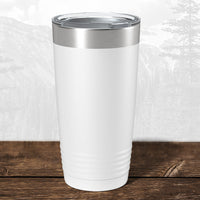 A white 20 oz Kodiak Coolers tumbler with a clear lid, laser engraved with the Wisconsin Green Bay Bulldogs, sits on wood with pride amid a mountain backdrop.