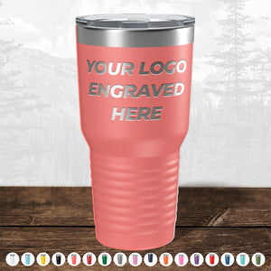 The Kodiak Coolers coral tumbler, part of a limited-time sale, features an engraved logo with no setup fees. It includes an open-mouth lid and metal rim, displayed against a nature backdrop. Ideal as a corporate promotional gift, it's available in various colors for bulk wholesale purchases.