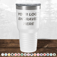 **Product Description:**
The white insulated tumbler from Kodiak Coolers features the custom engraving "YOUR LOGO ENGRAVED HERE" and is showcased on a wooden surface. Below, an array of colorful tumbler caps are displayed, against a subtle outdoor landscape backdrop. This makes it an ideal promotional gift for companies interested in personalized logos on custom mugs. Take advantage of our HUGE LABOR DAY SALE—ENDS TODAY!