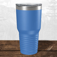 A 30 oz blue tumbler by Kodiak Coolers, featuring a laser-engraved Wisconsin Green Bay Bulldogs logo and clear lid, rests on wood with an outdoor background reminiscent of Green Bay, Wisconsin.