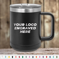 A black 15 oz custom coffee mug from Kodiak Coolers with "Your Logo Engraved Here," features a laser-engraved logo, silver lid and handle, displayed on wood. Various color options for these Kodiak Coolers mugs are available below.