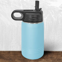 The Kodiak Coolers Wisconsin Green Bay Bulldogs 12 oz water bottle features a laser-engraved design, black flip-top straw lid, and carrying handle—ideal school drinkware for fans—shown on a wooden surface with a gray and white backdrop.